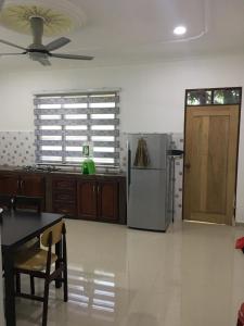 a kitchen with a refrigerator and a table and chairs at CM HOMESTAY in Kampung Raja