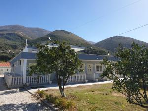 a large white building with mountains in the background at Aparthotel Fitimi in Borsh