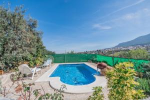 a swimming pool in a backyard with a green fence at Cubo's Finca Jara in Alhaurín el Grande