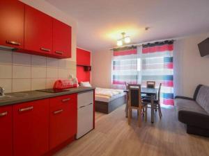 a kitchen with red cabinets and a table and a bed at Willa Natenczas in Jarosławiec