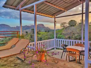 a porch with a table and chairs and a view of mountains at Forest Eco Lodge in Mount Ābu