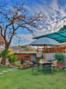 a table and chairs with an umbrella in a yard at Forest Eco Lodge in Mount Ābu