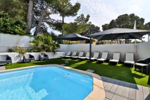 - une piscine avec des chaises et des parasols dans l'arrière-cour dans l'établissement Hotel La Tuiliere, à Carry-le-Rouet