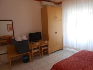 a bedroom with a bed and a desk with a television at PENSIONE VERDE LUNA in Orbetello