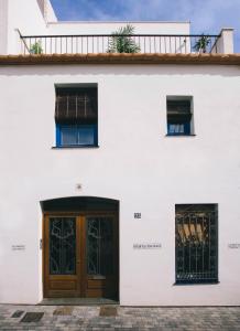 a white building with a wooden door and two windows at Sans Souci Quality Apartments in Sitges