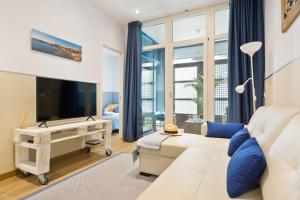 sala de estar con sofá blanco y TV de pantalla plana en Sans Souci Quality Apartments, en Sitges