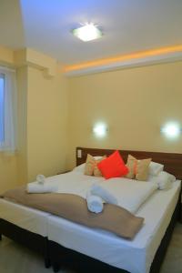a bedroom with a large bed with red and orange pillows at Mária Apartman Pécs in Pécs