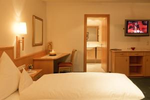 een slaapkamer met een wit bed en een badkamer bij Hotel Angelika in Sankt Anton am Arlberg