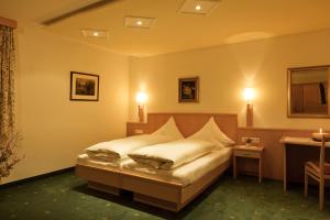 Schlafzimmer mit einem Bett, einem Tisch und Lampen in der Unterkunft Hotel Angelika in Sankt Anton am Arlberg