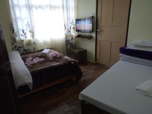 a room with two beds and a window with a television at Green Tara Residency in Darjeeling