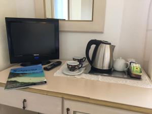 a desk with a television and a coffee pot and a book at Hotel Sorgente in Aglientu