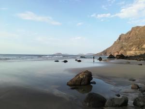 a beach with a large rock in the sand at El Charquito in Famara
