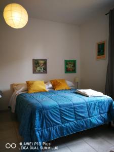 Dormitorio con cama con edredón azul y almohadas amarillas en Villa Galilei Rooms, en Pisa