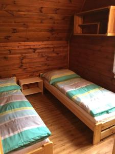 two beds in a cabin with wooden walls at Chata Pod Bílým kamenem in Doksy