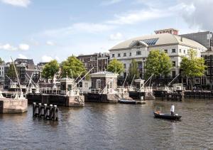 un hombre en un barco en un río con edificios en SWEETS - Amstelschutsluis, en Ámsterdam