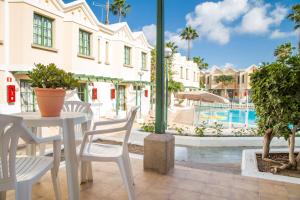 un patio con tavolo, sedie e piscina di Complejo Sun's Gardens - Maspalomas a Maspalomas