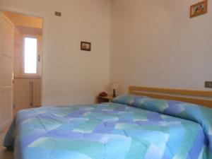 a bedroom with a bed with a blue comforter at PENSIONE VERDE LUNA in Orbetello
