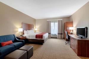 a hotel room with a bed and a couch and a tv at Comfort Inn and Suites Fredericksburg in Fredericksburg