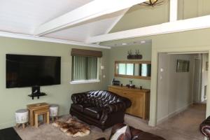a living room with a leather couch and a flat screen tv at The Sheiling in Dornie