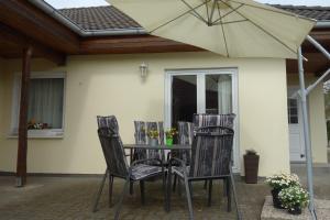 een tafel met stoelen en een parasol op een patio bij Heydens Ferienhaus_HEYD in Ostseebad Karlshagen