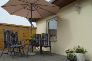 a table and chairs with an umbrella on a patio at Heydens Ferienhaus_HEYD in Ostseebad Karlshagen