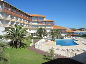un hotel con piscina, palmeras y un complejo en Résidence Mer & Golf Le Boucanier Port d'Albret, en Vieux-Boucau-les-Bains
