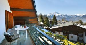 d'un balcon avec une table et une vue sur les montagnes. dans l'établissement Villars soleil, à Villars-sur-Ollon