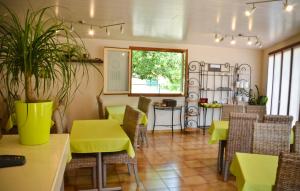 a restaurant with yellow tables and chairs and a plant at Hotel Les Pins in Hourtin