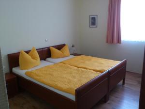 1 dormitorio con 2 camas con almohadas amarillas en Eifel - Pension, en Kall