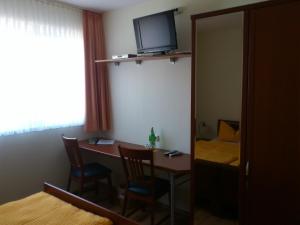 a room with a table with chairs and a television at Eifel - Pension in Kall