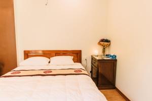 a bedroom with a bed with a wooden headboard and a table at Chi Homestay #3 in Hue