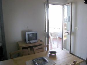 un soggiorno con TV e tavolo con tastiera di Appartamento uso piscina a Cala Gonone