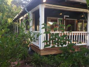 a small house with a porch in a garden at Lakeside Garden Chalet in Denmark