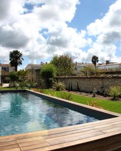 a swimming pool with a wooden deck in a yard at L’Ostréale in La Tremblade