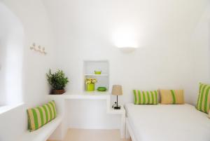 a white living room with green and white pillows at White Grape Suites in Oia