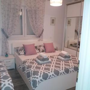 a bedroom with a bed with pink pillows and a mirror at Apartment Radalj in Kaštela