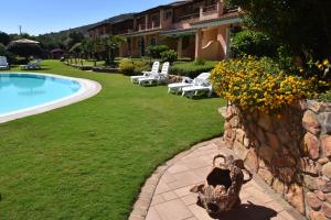 un complejo con piscina y pared de piedra en Su Giganti, en Villasimius