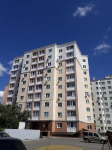 un gran edificio de apartamentos blanco con coches aparcados frente a él en Center Park Brovary en Brovary