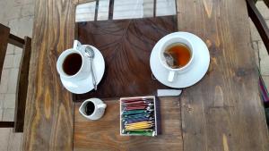a wooden table with two cups of coffee and aucer of tea at Ruta Alterna Hostel in Cajamarca