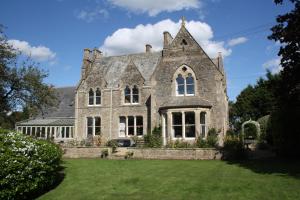 una antigua casa de piedra con un gran patio en The Rectory Lacock Cottages en Lacock