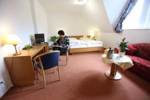 a man sitting on a bed in a hotel room at Hotel Cordial in Lennestadt