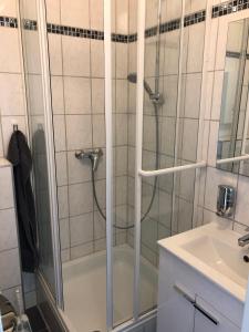 a shower with a glass door next to a sink at Ruhiges Apartment mit Blick in den Garten in Alsdorf