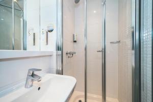 
a bathroom with a shower, sink, and mirror at Point A London Liverpool Street in London
