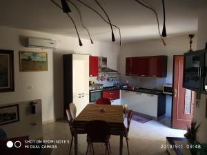 una cucina con tavolo e una cucina con armadi rossi di Alma a Porto Torres