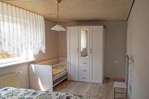 a bedroom with a crib and a white cabinet at Ferienwohnung Am-Brueckenrain in Frankenau