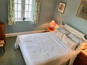 una camera da letto con un grande letto bianco e una finestra di Jago Cottage a Truro