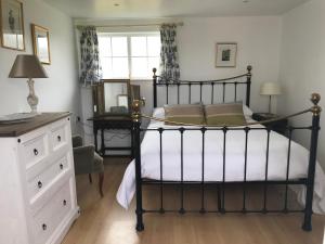 a bedroom with a bed and a dresser and a mirror at Jago Cottage in Truro