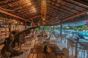 a restaurant with tables and chairs and a pool at Village Muta in Porto Seguro
