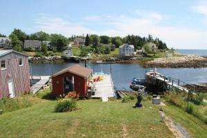 une petite maison à côté d'un quai avec un bateau dans l'établissement Sal's Bed and Breakfast by the Sea, à Herring Cove