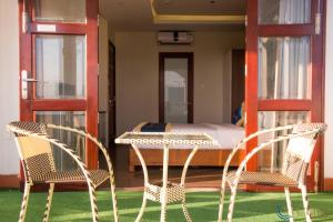 two chairs and a table in a room with a bed at C'Lavie Hotel - Saigon Airport Hotel in Ho Chi Minh City